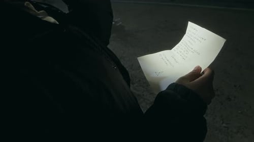 Person Reads Letter Using Flashlight at Night