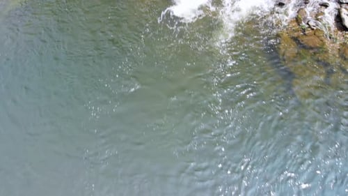 Aerial close up slow pan of a small creek with rapids, 23.976 frames per second