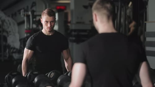 Ein sportlicher Mann führt eine Bizepsübung durch und hebt abwechselnd Hanteln