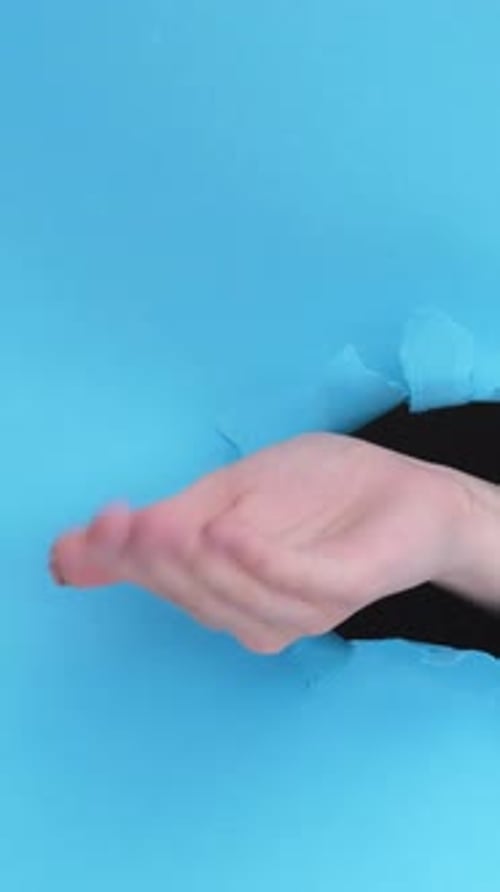 Hand Gesturing From Torn Blue Paper Background