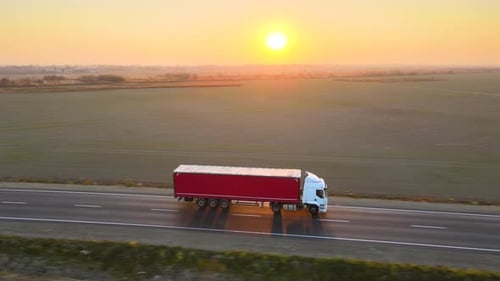 Aerial View of Semitruck with Cargo Trailer Driving on Highway Hauling Goods in Evening