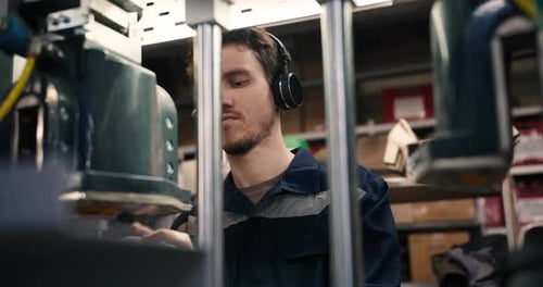 Man Wearing Headphones Working at Machine