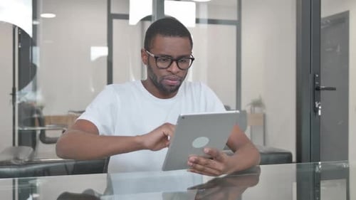 Young African Man Using Digital Tablet in Office