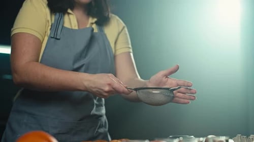 A Female Baker Sprinkling Cinnamon on an Apple Pie