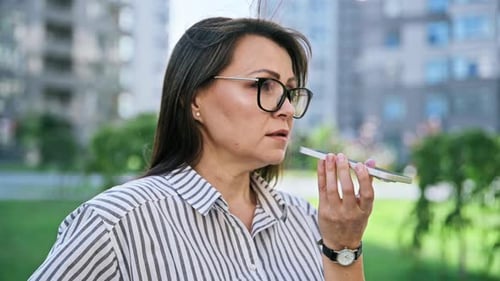 Mature Woman Recording Audio Message on Smartphone Outdoors Street Urban Style
