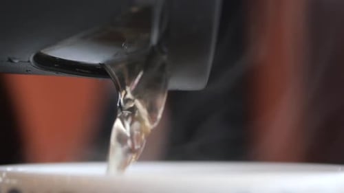 Pours Tea From a Teapot Into a Cup