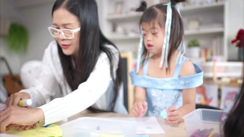 Teacher Assists Children with Arts and Crafts Activity