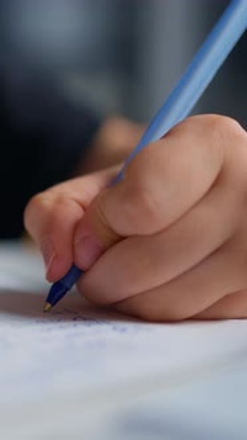 Closeup Shots of a Person Writing in a Notebook with a Blue Pen Focusing on the Hand Gripping the