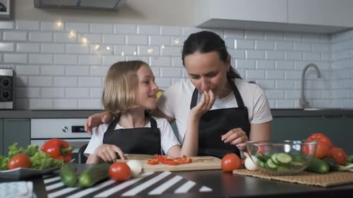 Daughter Feeds Mom Bell Pepper While Cooking