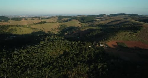 Moving forward with Drone filming mountains and large trees in lush green countryside, in resolution