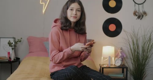 Teenage Girl Using Smartphone Sitting on Her Bed