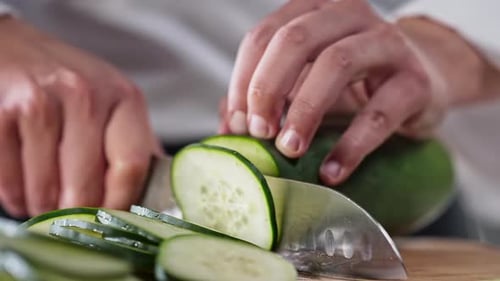 Chef slicing cucumber in slow motion