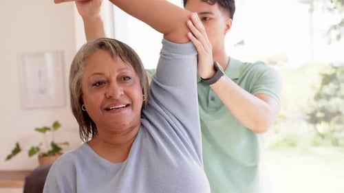 Physiotherapist assisting senior woman with arm stretching exercise in clinic