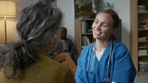 Female Caregiver Supporting Elderly Woman in Nursing Home