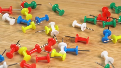 Colorful push pins rotating on the desk. Drawing pins for marking on the map of the Earth or city