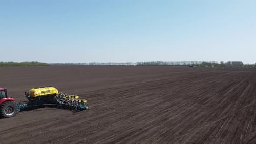 Tractor with yellow seeder working on the field in Ukraine OA Lexa