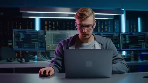 Man Working on Laptop with Multiple Computer Screens