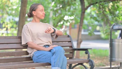 Woman Sitting on Park Bench Checking the Time