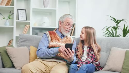 Grandfather and Granddaughter Looking at Smartphone Together