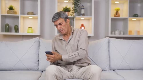 Old man laughing at phone message.