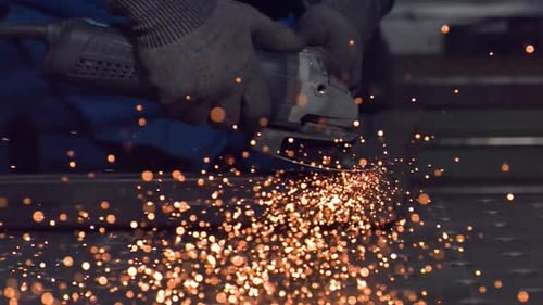 Metalworker Grinding Steel with Angle Grinder, Sparks Flying