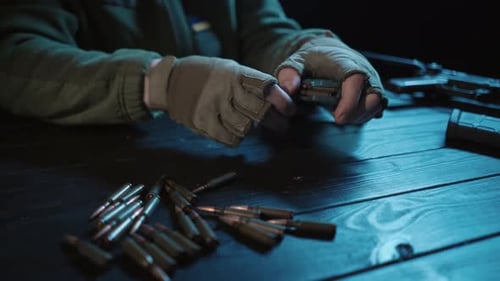 Hands Reloading a Gun Magazine With Bullets