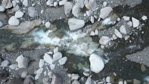Slow motion drone top down view following clear flowing river