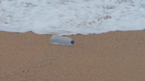 Plastic water bottle on the beach, pollution, garbage, waves in slow motion, ecology, pollution, a w