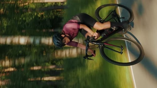 Female cyclist riding bicycle fast in park. Vertical video