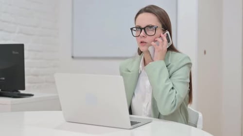 Professional Woman on Phone and Laptop in Office