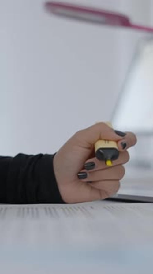A Young Student Sitting at a Table and Reading Her Study Material and Holding a Highlighter in Her