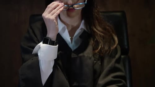 Woman Judge Removes Glasses at Courtroom Desk