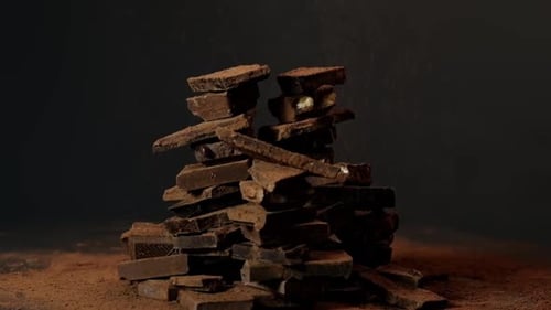 Chocolate Pieces Stacked with Cocoa Powder Falling