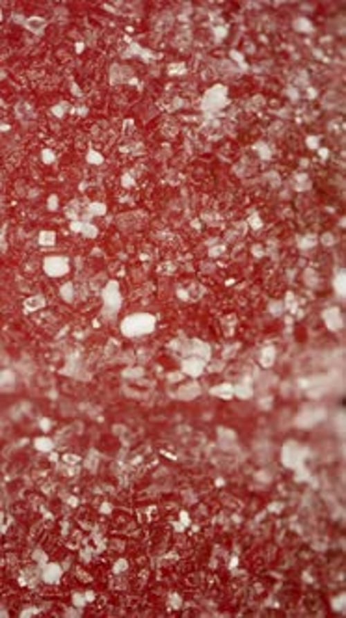 Vertical video. Gummy candy in the shape of a cherry in sugar, simulated falling on a black