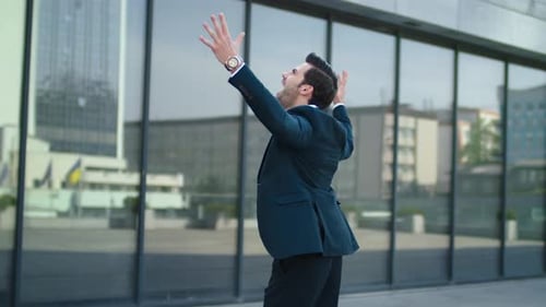 Close Up Cheerful Man Raising Hands In Stylish Suit At Street. Handsome Businessman Celebrating V...