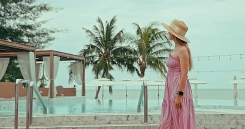 Woman in hat at luxury resort pool - Tropical vacation lifestyle