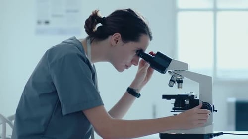Young Woman Using Microscope in Medical Lab