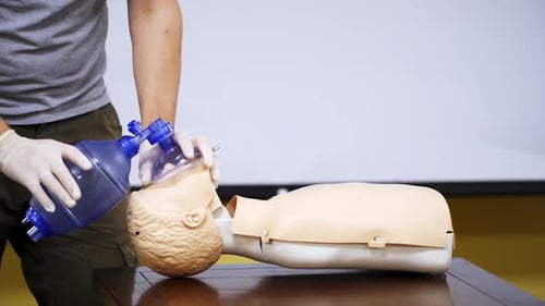 Training in medical center. Person in protective gloves giving breath exercise on a dummy.