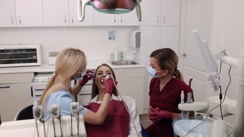 Dentist Examining Patient's Teeth with Assistant
