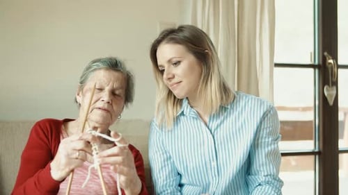 Senior Woman Knitting, Assisted by a Young Woman