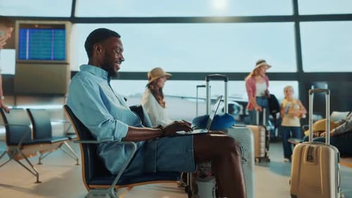 Un homme travaille sur son ordinateur portable alors qu'il attend dans le terminal de départ d'un aéroport.