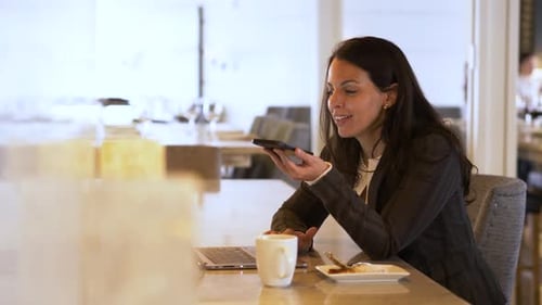 Businesswoman Talking on Smart Phone at Laptop in Restaurant 4044 Years