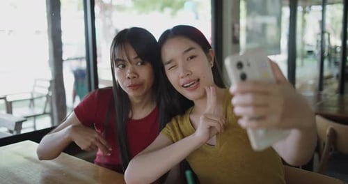 Two siblings taking a selfie on mobile phone at a coffee shop.