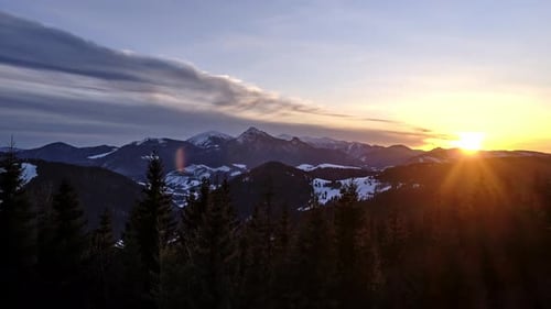 Timelapse of Colorful Sunset Over Winter Mountain Peaks with Silhouettes of Forest Trees