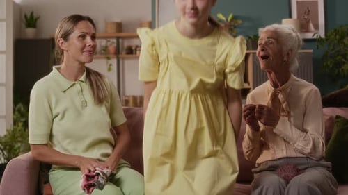 Smiling Teenage Girl Posing with Mother and Grandmother on Sofa