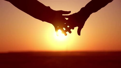 Closeup Romantic View of Couple Holding Hands Against Blurred Sky and Sunset