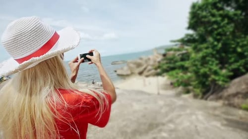 Femme prenant une photo du bord de mer