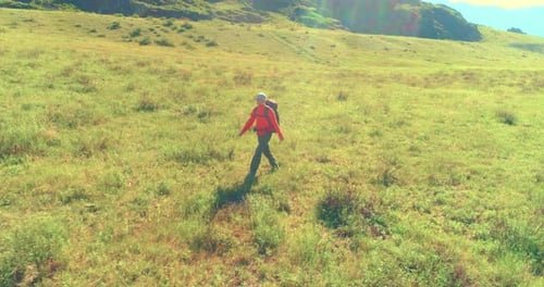 Flight Over Backpack Hiking Tourist Walking Across Green Mountain Field Huge Rural Valley at Summer