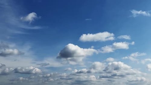 White small fluffy clouds transform in the blue sky. Cumulus clouds change shape in the atmosphere.