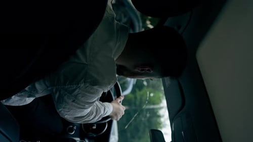 vertikales Video, Rückansicht: Ein Mann, ein Geschäftsmann, fährt mit einem Luxusauto durch die Stadt, ein schwarzes Leder
